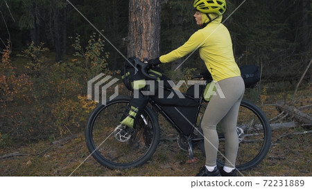 The woman travel on mixed terrain cycle touring with bike bikepacking. The traveler journey with bicycle bags. Magic forest park. 72231889
