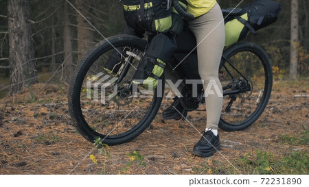 The woman travel on mixed terrain cycle touring with bike bikepacking. The traveler journey with bicycle bags. Magic forest park. The woman travel on mixed terrain cycle touring with bike bikepacking. The traveler journey with bicycle bags. Magic forest park. 72231890
