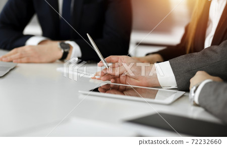 Unknown businessmen and woman sitting, using laptop computer and discussing questions at meeting in sunny office, close-up. Success concept 72232660