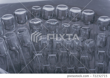 Glass medical ampoule vial for injection. Medicine is liquid sodium chloride with of aqueous solution in ampulla. Close up. Bottles ampule multicolor. 72232715