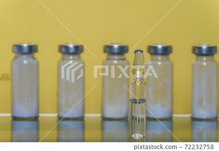 Glass medical ampoule vial for injection. Medicine is liquid sodium chloride with of aqueous solution in ampulla. Close up. Bottles ampule multicolor. Glass medical ampoule vial for injection. Medicine is liquid sodium chloride with of aqueous solution in ampulla. Close up. Bottles ampule multicolor. 72232758