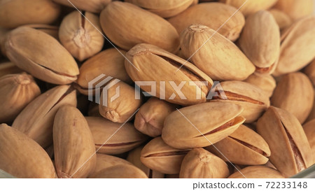 Nuts pistache rotate are on a table in a plate. Snack in transparent dish on an isolated white background are spinning moving. 72233148