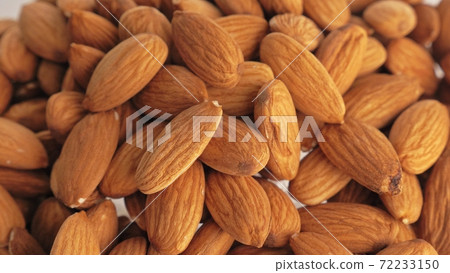 Nuts almond rotate are on a table in a plate. Snack in transparent dish on an isolated white background are spinning moving. 72233150