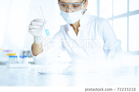 Female laboratory assistant analyzing test tube with blue liquid. Medicine, health care and researching concept 72233218