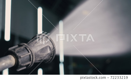 Water hose car washing close up. Worker man watering with foam auto out of manually high pressure hose jet in car wash. Spraying wash car with soap. 72233219