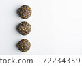 Diet vegetarian energy balls with nuts, dried fruit, oats, cocoa, peanut butter and honey, topped with chia seeds. White background. 72234359