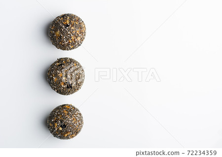 Diet vegetarian energy balls with nuts, dried fruit, oats, cocoa, peanut butter and honey, topped with chia seeds. White background. Diet vegetarian energy balls with nuts, dried fruit, oats, cocoa, peanut butter and honey, topped with chia seeds. White background. 72234359