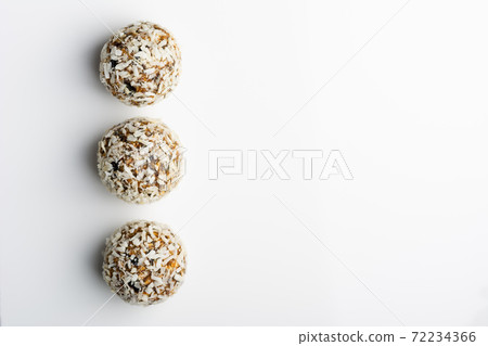 Diet vegetarian energy balls with nuts, dried fruit, chia, oats, cocoa, peanut butter and honey in coconut flakes. White background. Diet vegetarian energy balls with nuts, dried fruit, chia, oats, cocoa, peanut butter and honey in coconut flakes. White background. 72234366