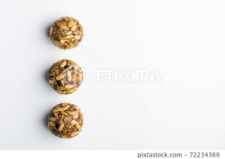 Diet vegetarian energy balls with nuts, chia, sunflower, dried fruit, oats, cocoa, peanut butter and honey. White background. Diet vegetarian energy balls with nuts, chia, sunflower, dried fruit, oats, cocoa, peanut butter and honey. White background. 72234369
