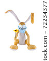 A soft toy hare with a flower and in a medical mask with the inscription visitor. White background. Humor. Mockery. Isolate. 72234377