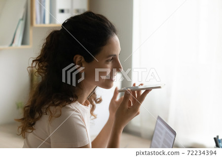 Close up smiling woman holding smartphone, recording voice message 72234394