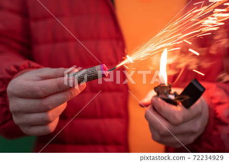 Man in Red Jacket Lighting Up Firecracker in his Hand 72234929