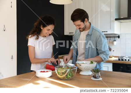 Happy pleasant family cooking together, cutting vegetables in kitchen 72235004