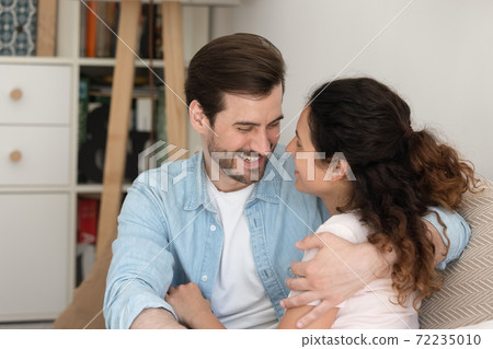 Close up happy young couple hugging, looking in eyes with love Close up happy young couple hugging, looking in eyes with love 72235010