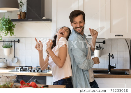 Overjoyed young family having fun in modern kitchen, dancing, laughing 72235018