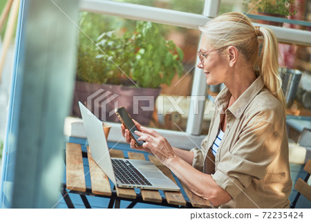 Middle aged caucasian woman dialing number on phone Middle aged caucasian woman dialing number on phone 72235424