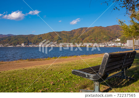Bench along the lakeside in autumn with autumn leaves 72237565