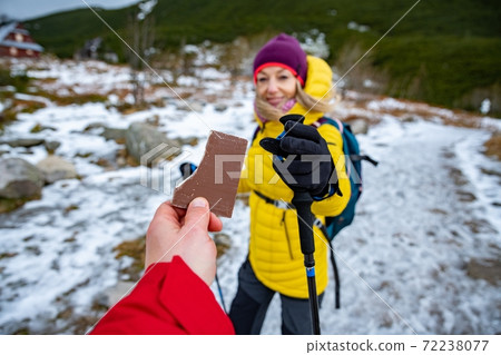 Tourist couple sharing with delicious chocolate snack bar on the winter trail 72238077
