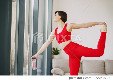 Girl in a red sports uniform make yoga at home Girl in a red sports uniform make yoga at home 72240792