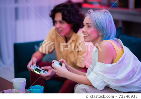 Handsome young man teaching how to play the video games to his girlfriend, on the couch, concept about home entertainment, video games. 72240933