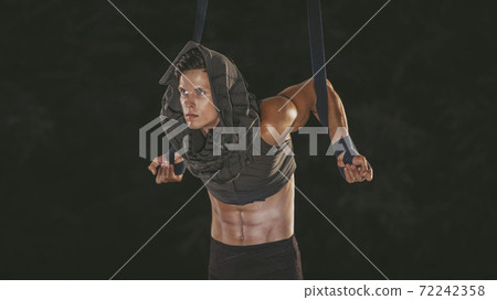 Beautiful young acrobat makes pull-ups on ropes 72242358