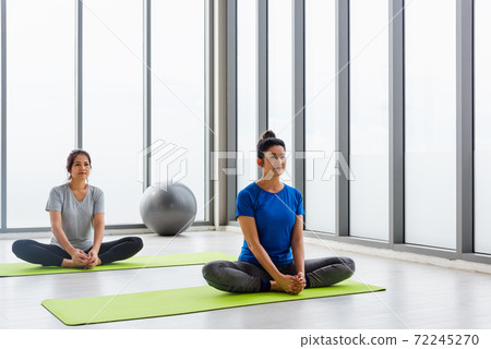 Two Asian women sporty attractive people practicing yoga lesson together 72245270