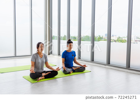 Two Asian women sporty attractive people practicing yoga lesson together 72245271