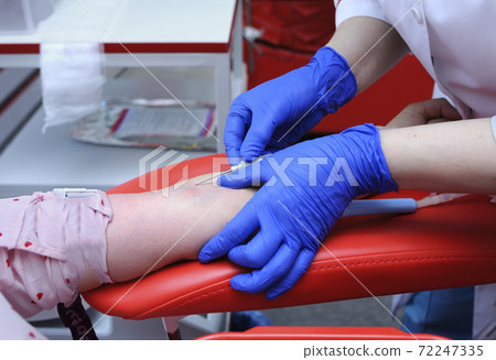 Nurse hands taking blood from the vain of a donor - hypodermic needle, tubes, container with blood Nurse hands taking blood from the vain of a donor - hypodermic needle, tubes, container with blood 72247335