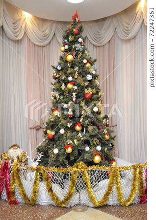 Christmas tree decorated with toys and ornaments set in a hall before New Year Day Christmas tree decorated with toys and ornaments set in a hall before New Year Day 72247361