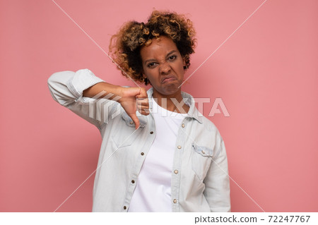African young woman doing a thumbs down signal with her hand. African young woman doing a thumbs down signal with her hand. 72247767
