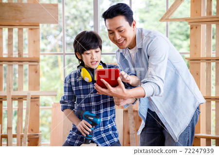 Asian father and son looking at digital tablet in carpentry workshop at home. Asian father and son looking at digital tablet in carpentry workshop at home. 72247939