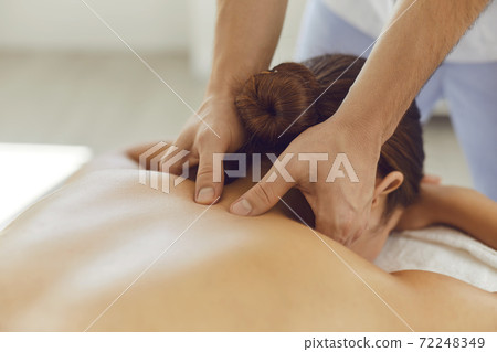 Young woman enjoying relaxing remedial body massage done by professional masseur 72248349