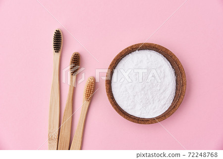 Three wooden bamboo toothbrushes and baking soda on pink background, top view Three wooden bamboo toothbrushes and baking soda on pink background, top view 72248768