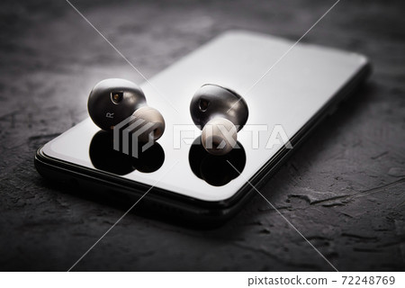 Wireless earphones on smartphone. Bluetooth headphones for listen audio 72248769