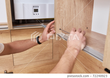 Male carpenter install shelf in kitchen cabinet Male carpenter install shelf in kitchen cabinet 72248923