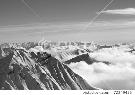 Snowy mountains in clouds at nice winter day 72249456