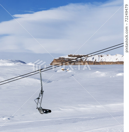 Snowy slope, chair-lift and blue sky with clouds at sun winter day 72249479