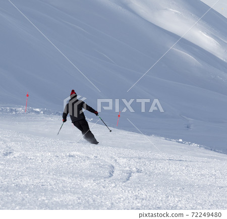 Skier downhill on prepared snowy ski slope at winter day 72249480