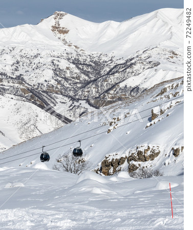 Snow-covered off-piste ski slope in snowy mountains and gondola lift 72249482