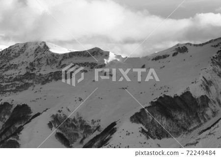 Snowy slope for freeriding and sunlight mountains in clouds 72249484