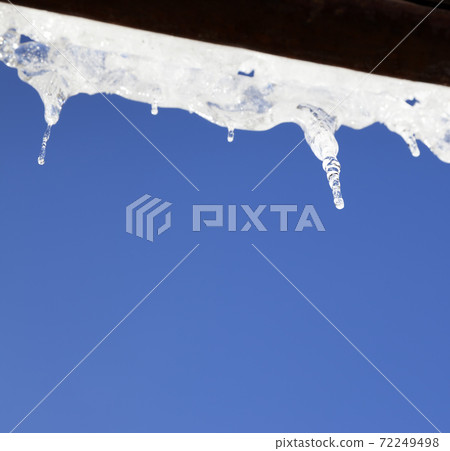 Wooden roof with snow cornice and sunlight icicles 72249498