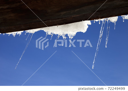 Wooden roof with snow cornice and icicles at sun winter day 72249499