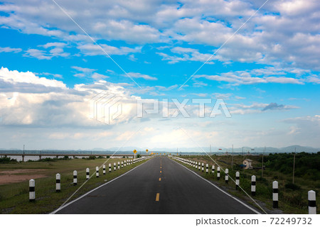 View of the asphalt highway and clouds on blue sky in summer day. A delightful view of a road passing into the horizon line on a beautiful summer day View of the asphalt highway and clouds on blue sky in summer day. A delightful view of a road passing into the horizon line on a beautiful summer day 72249732