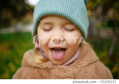 portrait of a little cute girl with sticking out tongue portrait of a little cute girl with sticking out tongue 72250131