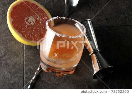 Salty dog with salt on the edge of the glass, cut grapefruit, spoon and measure cup 72252230