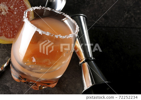 Salty dog with salt on the edge of the glass, cut grapefruit, spoon and measure cup 72252234