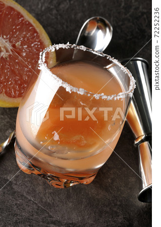 Salty dog with salt on the edge of the glass, cut grapefruit, spoon and measure cup 72252236