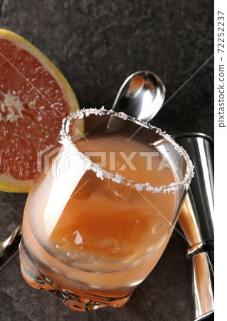 Salty dog with salt on the edge of the glass, cut grapefruit, spoon and measure cup 72252237