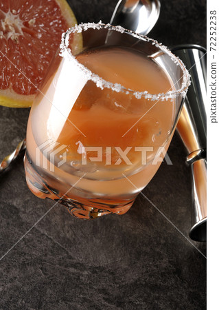 Salty dog with salt on the edge of the glass, cut grapefruit, spoon and measure cup 72252238