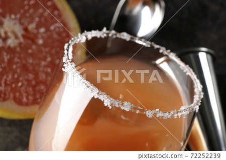 Salty dog with salt on the edge of the glass, cut grapefruit, spoon and measure cup 72252239